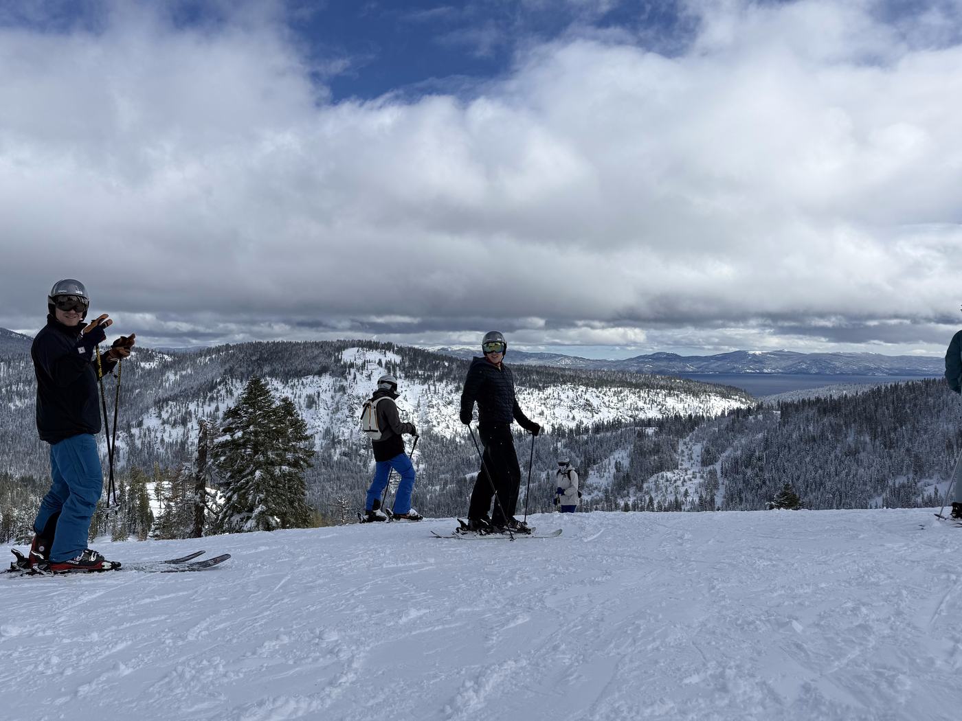 Skiers on a groomed run above Olympic Valley with Lake Tahoe in the distance